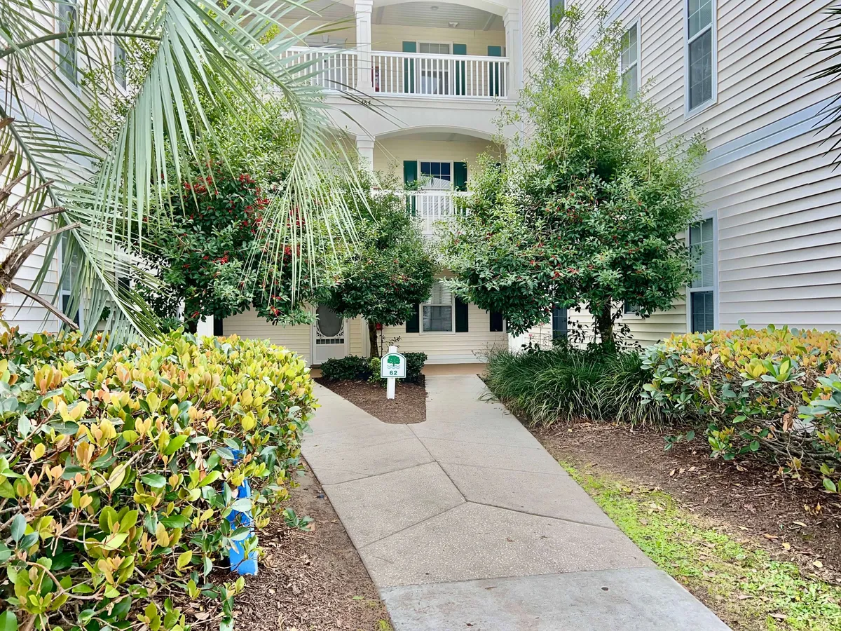 This image highlights lush green landscaping with a pathway leading to the entrance and visible balcony views above. The environment feels welcoming and serene, suggesting opportunities for leisurely strolls and enjoying private outdoor spaces.