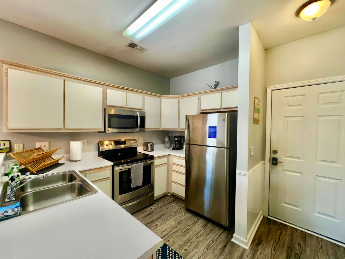 A bright, open kitchen space highlights sleek stainless steel appliances and crisp white cabinetry. The generous countertop and open layout are ideal for entertaining and preparing elaborate meals, capturing the sophisticated yet inviting promise of the section.